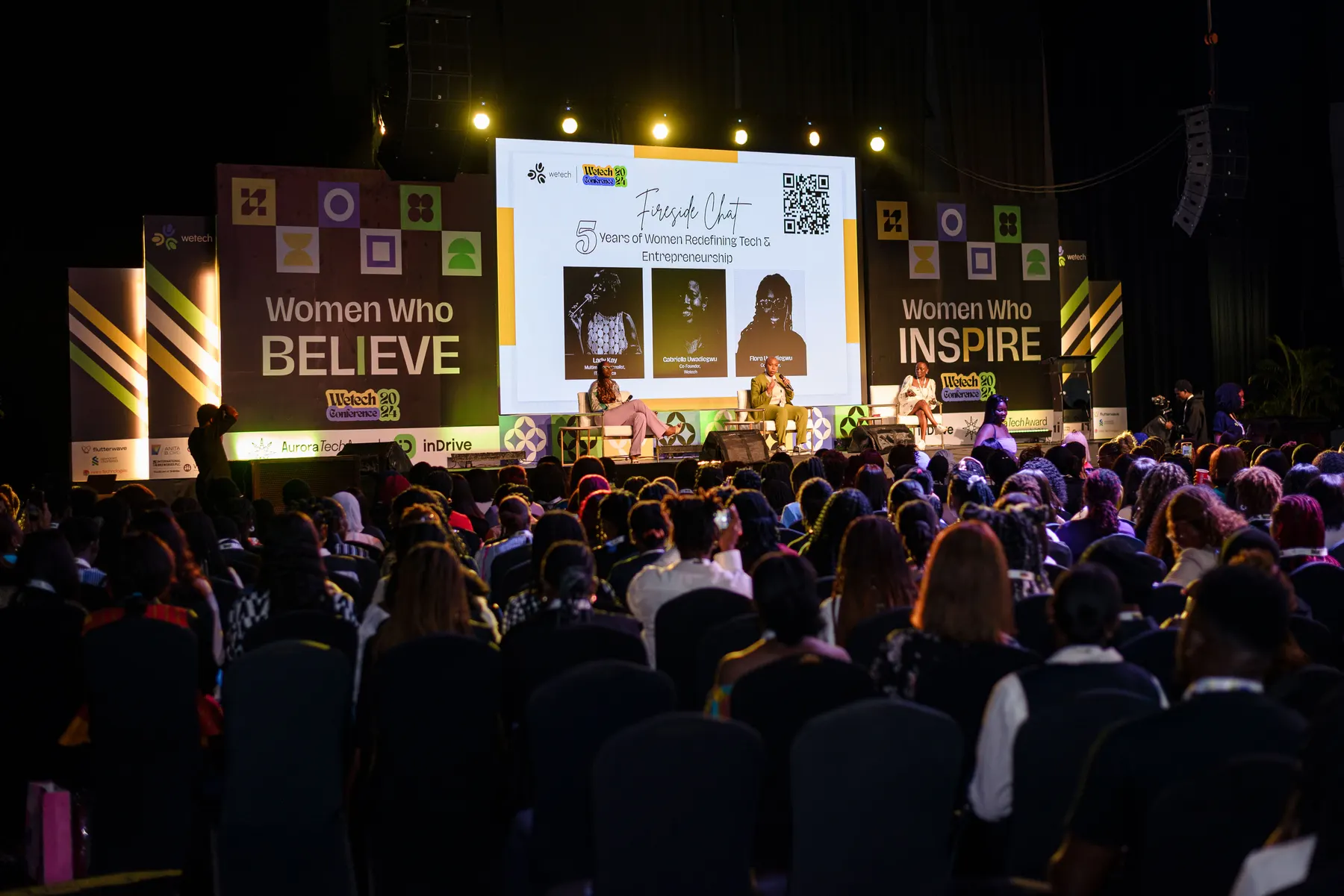 Women Who Believe / Women Who Inspire — flanking stage panels.