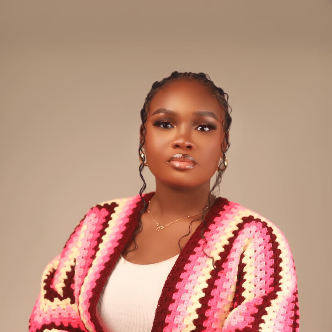 Adenike Adedokun, arms folded, in a hand-crocheted striped cardigan